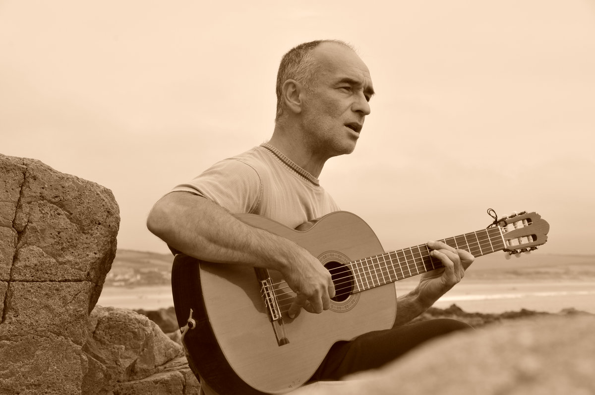 Jean-René Dalerci jouant de la guitare au bord de la mer